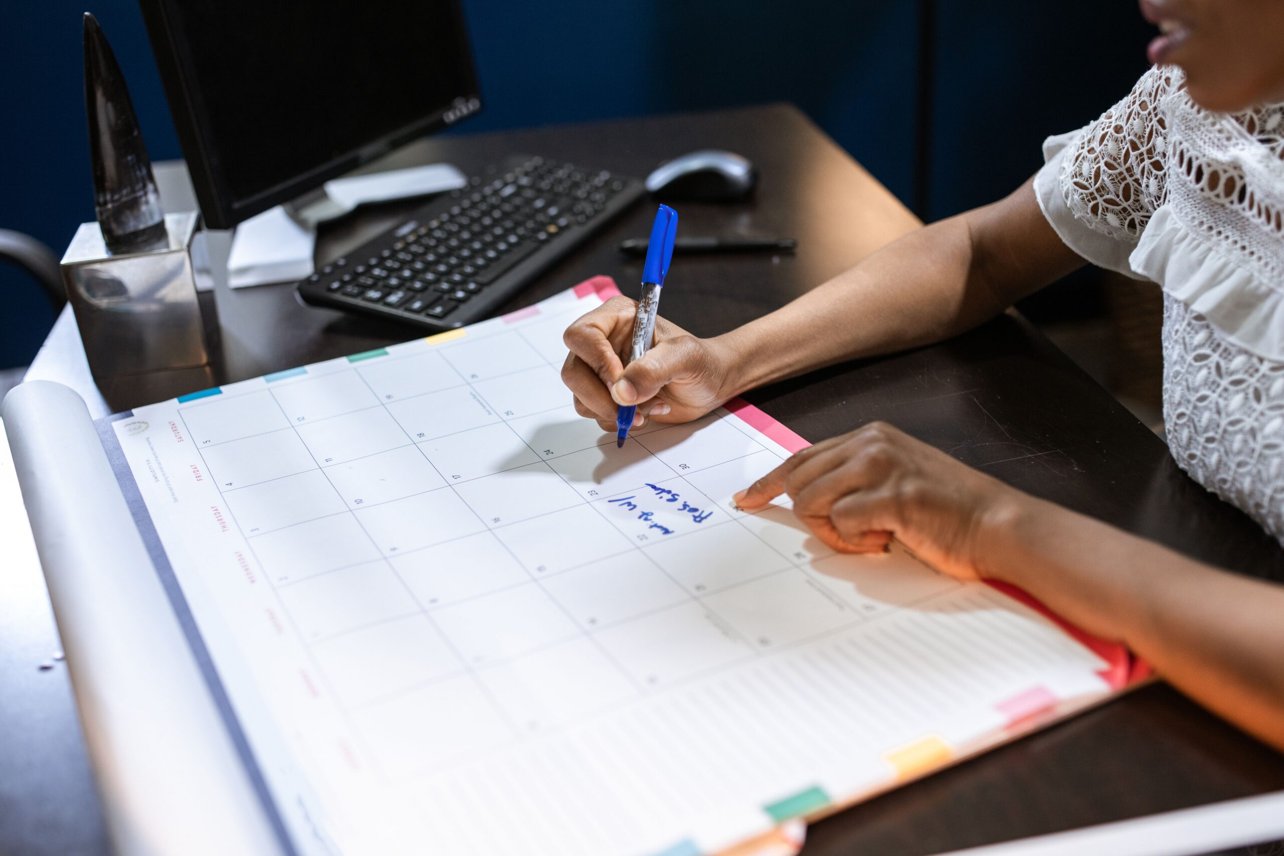 Black South African entrepreneur planning business deadlines on a desk calendar.