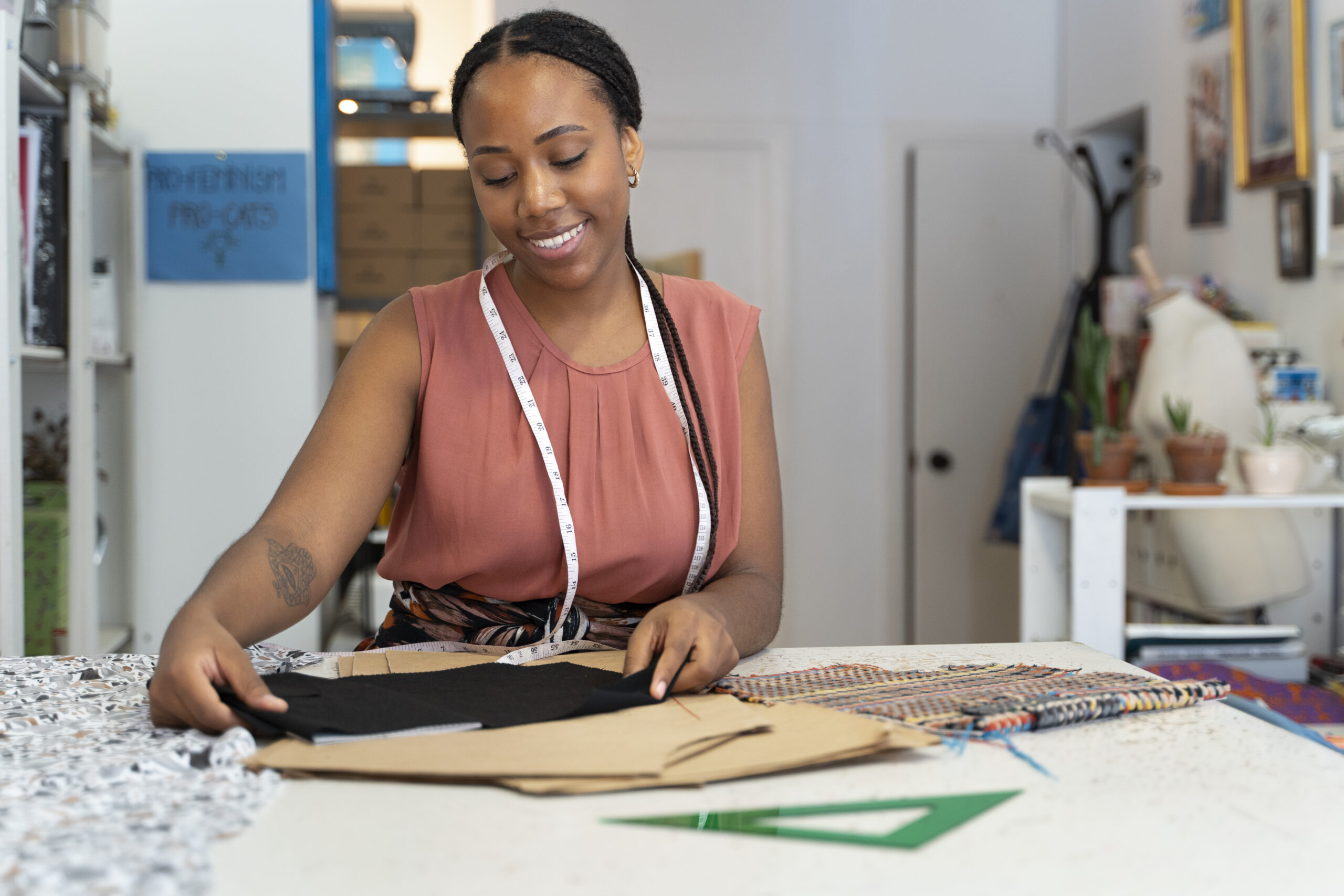 Black South African fashion entrepreneur measuring and cutting fabric in her design studio.